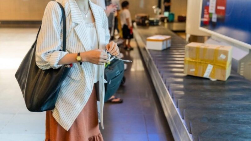 Seorang wisatawan menyiapkan paspor dan tiket penerbangan di bandara internasional sambil memegang dokumen asuransi perjalanan yang memberikan perlindungan selama berada di luar negeri.