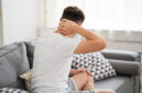 Neck pain, man suffering from ache at home, health problems concept